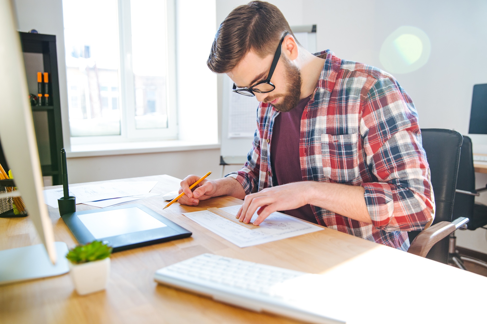 Portrait of young male designer sitting and making blueprint